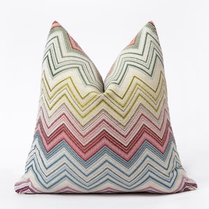 May include: A decorative pillow with a colorful chevron pattern in shades of pink, green, blue, and yellow. The pillow is made of a soft, textured fabric.