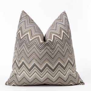 May include: A decorative throw pillow with a chevron pattern in shades of brown, beige, and grey.