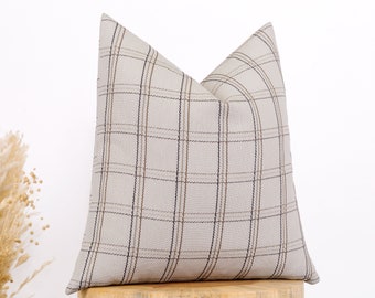 May include: A beige throw pillow with a brown and black plaid pattern.