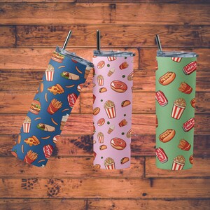 May include: Three stainless steel tumblers with different fast food designs. The first tumbler is blue with a pattern of pizza slices, french fries, burgers, and ice cream cones. The second tumbler is pink with a pattern of donuts, popcorn, tacos, and ice cream cones. The third tumbler is green with a pattern of hot dogs, french fries, popcorn, and soda cans.