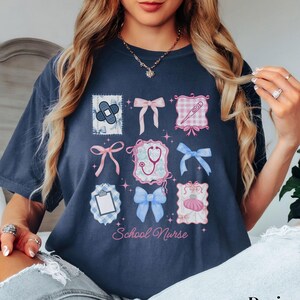 May include: A navy blue t-shirt with a graphic design of pink and blue bows, a stethoscope, a bandage, a thermometer, and a clipboard. The text "School Nurse" is printed on the shirt.