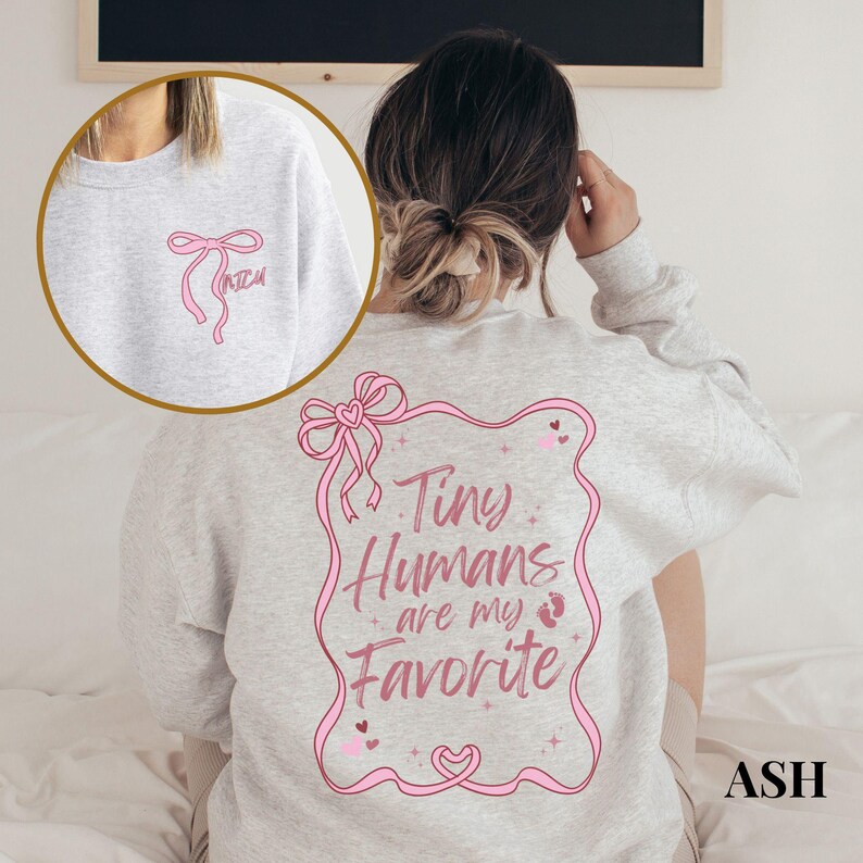 May include: A gray sweatshirt with a pink bow on the front and the text "Tiny Humans are my Favorite" in a pink frame on the back.