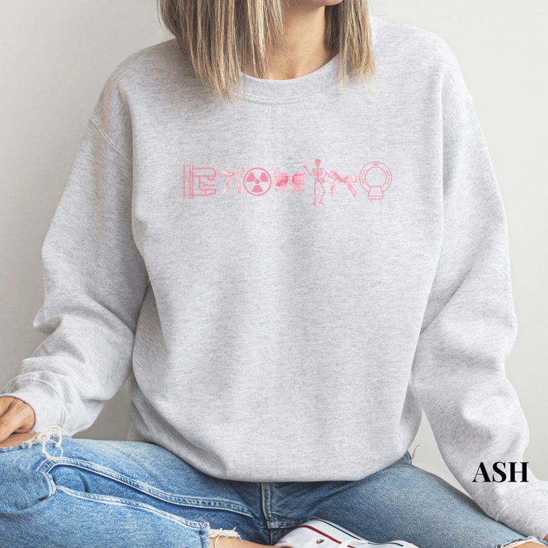 May include: A gray sweatshirt with a pink graphic of a series of medical symbols, including a radiation symbol, a skeleton, and a medical scanner.
