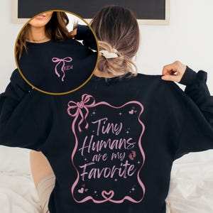 May include: Black sweatshirt with a pink ribbon and the text "Tiny Humans are my Favorite" in a pink frame with hearts and stars.
