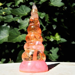 Peut inclure: Une corne de licorne rose et orange en résine avec des paillettes dorées. La corne est en couches et a une forme en spirale.