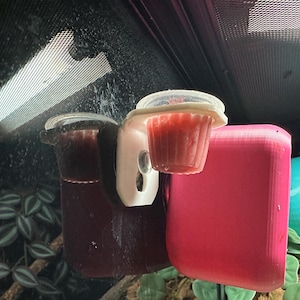 Könnte beinhalten: Terrarieneinrichtung mit einem transparenten Plastikbecher mit einer roten Substanz, einem weißen Spender und einem dunkelroten Behälter. Ein leuchtend pinkfarbener quadratischer Behälter und eine türkisfarbene Schale sind ebenfalls sichtbar.