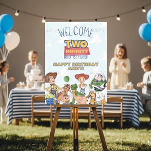 Puede incluir: Un caballete de madera muestra un letrero de cumpleaños colorido con el texto "Welcome Two Infinity and Beyond! Happy Birthday Andy!" con personajes de Toy Story. Globos azules y blancos en el fondo.