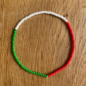 Könnte beinhalten: Eine grüne, weiße und rote Perlenkette. Die Perlen sind in einem Kreis angeordnet, wobei die grünen Perlen unten, die weißen Perlen in der Mitte und die roten Perlen oben sind.