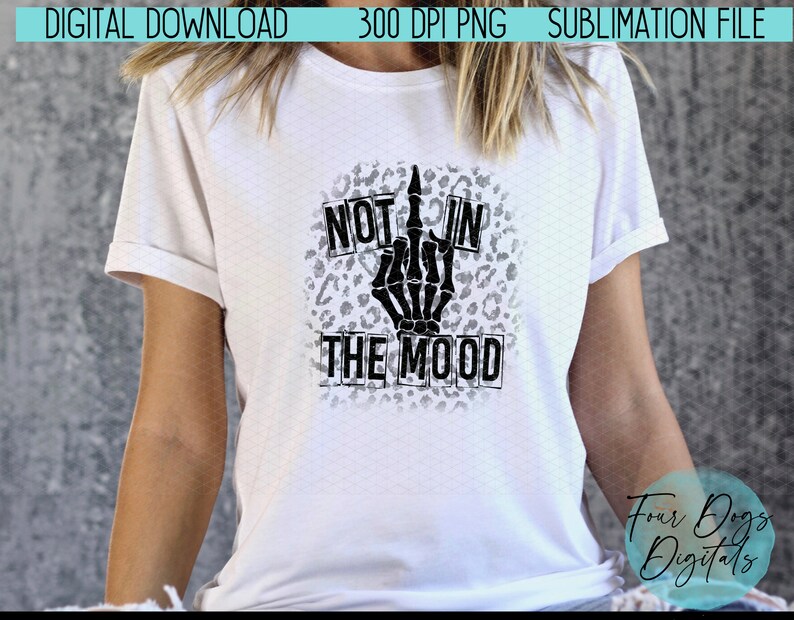 May include: A white t-shirt with a black skeleton hand giving the middle finger, with the words "Not in the mood" in black boxes on a leopard print background.