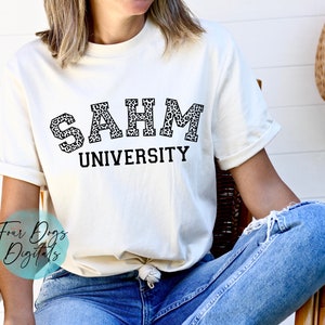 K&ouml;nnte beinhalten: Ein wei&szlig;es T-Shirt mit dem Aufdruck "SAHM UNIVERSITY". Die Buchstaben sind in einem schwarzen Leopardenmuster.