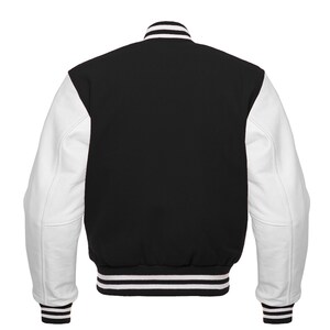May include: A black and white varsity jacket with white leather sleeves. The jacket has a ribbed collar, cuffs, and waistband.