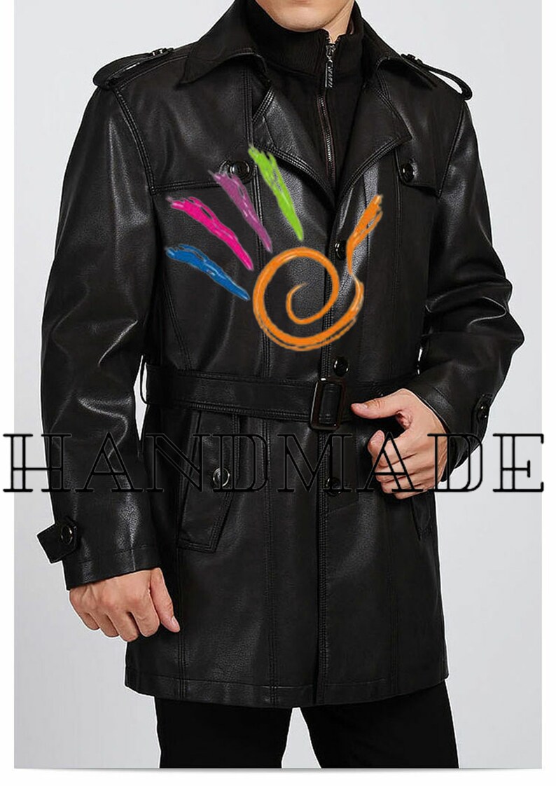 Pu&ograve; includere: Un trench in pelle nera con cintura e chiusura a doppio petto. Il cappotto ha un colletto e due tasche sul davanti. Il testo "HANDMADE" &egrave; visibile nella parte inferiore dell'immagine.