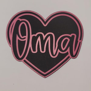 May include: A black heart-shaped design with the word "Oma" in pink script. The word is outlined in pink, and the heart shape has a pink border. The design is on a white background.