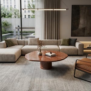 Peut inclure: Salon moderne avec un grand canapé d'angle beige, une table basse en marbre rouge et un fauteuil en cuir marron. La pièce dispose de grandes fenêtres donnant sur un jardin et une palette de couleurs neutres.