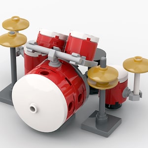 May include: A miniature red and white toy drum kit with gold-coloured cymbals. The drum kit includes a large bass drum, two smaller tom-toms, and two cymbals. The set is constructed from interlocking plastic bricks and sits on grey bases.