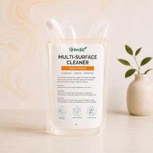 May include: A clear 1L plastic pouch of Arbortill Multi-Surface Cleaner in Sweet Orange. The label features black text, an orange accent bar, and three circular icons representing naturally derived, family friendly, and essential oil ingredients.