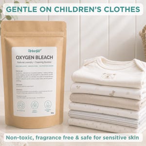 May include: A brown paper pouch of Arborfill Oxygen Bleach Natural Laundry and Cleaning Booster, 1kg, next to a stack of folded white and cream baby bodysuits. The label text includes instructions, ingredients, and icons for multipurpose, family friendly, and fragrance free use.