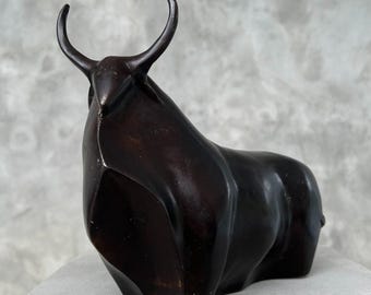 May include: A black bronze sculpture of a stylized bull with a geometric design. The sculpture is abstract and modern in style.