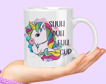 May include: White ceramic mug featuring a colourful unicorn illustration and the text "SHUH DUH FUH CUP".