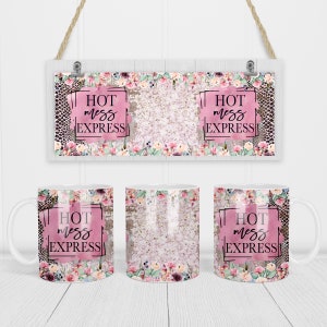 以下が含まれることがあります： ピンクの花柄と黒い正方形の中に「Hot mess express」という文字が書かれた白いマグカップが3つあります。マグカップは白い木製の表面の上に置かれています。