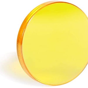 Puede incluir: Un filtro redondo de vidrio amarillo para fotografía o videografía.