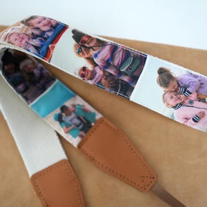 May include: A camera strap featuring a cream-colored woven strap with photo prints. The strap has brown leather ends and a brown strap for attaching to a camera. The photos show people in various settings.