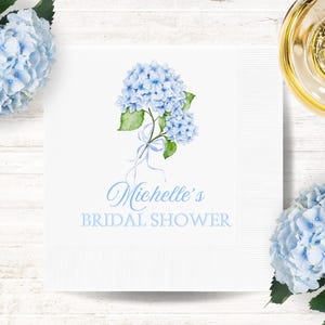 May include: White paper napkin with a blue hydrangea illustration and the text "Michelle's Bridal Shower".