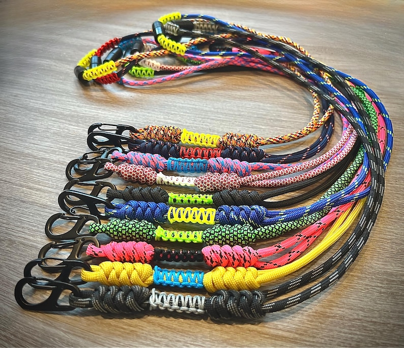 Puede incluir: Una colecci&oacute;n de cordones de paracord coloridos con cierres met&aacute;licos. Los cordones est&aacute;n hechos con diferentes colores y patrones de paracord.