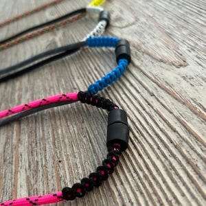 Puede incluir: Tres cordones trenzados de colores con cierres ajustables negros. Los cordones son rosa, azul y blanco.