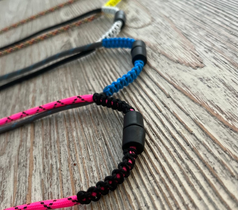 Puede incluir: Tres cordones trenzados de colores con cierres ajustables negros. Los cordones son rosa, azul y blanco.