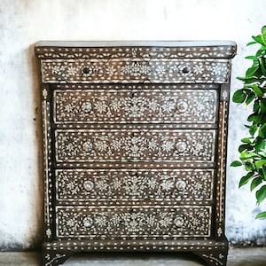 Op de afbeelding: Een donkerbruine houten dressoir met vijf laden. Elke lade is versierd met ingewikkelde bloemmotieven ingelegd met parelmoer.