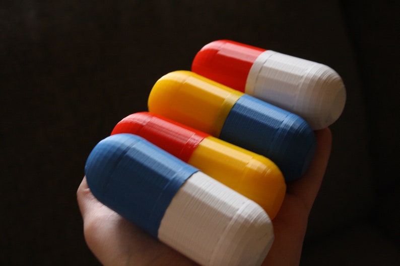 Hand Holding Screwed Shut Multicolored Small Storage Capsules - Red, White, Blue, and Yellow Compact Organizers. The capsules are securely screwed shut.