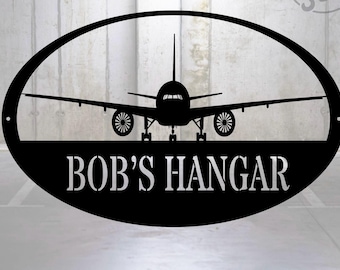 May include: Black metal oval sign with a silhouette of an airplane and the text "BOB'S HANGAR" in white.