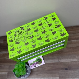 May include: A bright green three-drawer tool box with a black and white marijuana leaf pattern. The top drawer has the text "In a world full of Karens, be a Mary Jane" printed on it.