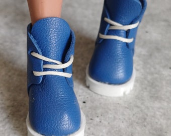 May include: A pair of blue leather doll boots with white laces and white soles.