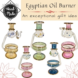 Könnte beinhalten: Eine Sammlung von fünf Glas-Ölbrennern mit goldfarbenen Rändern, die verschiedene farbige Glasakzente und tierförmige Details aufweisen. Der Text "Egyptian Oil Burner" und "Hand Made" ist oben im Bild deutlich zu erkennen.