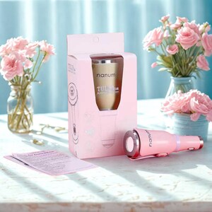 Pode incluir: Um conjunto de ambientador de carro rosa com um difusor dourado dentro de uma caixa rosa. A caixa tem o texto "nanum TULIP Car Aroma Diffuser". Um carregador de carro rosa também está incluído. Flores rosas em vasos no fundo.