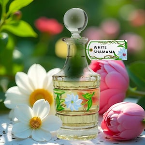 May include: A clear glass perfume bottle with a round stopper, filled with a yellow liquid. The bottle is decorated with painted flowers and the text "WHITE SHAMAMA". The background features white flowers and pink tulips.