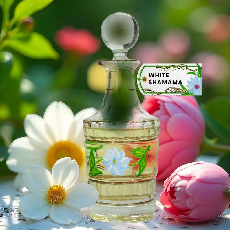 May include: A clear glass perfume bottle with a round stopper, filled with a yellow liquid. The bottle is decorated with painted flowers and the text "WHITE SHAMAMA". The background features white flowers and pink tulips.