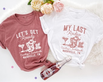 Puede incluir: Dos camisetas con un tema de despedida de soltera. La camiseta rosa dice "Let's Get Rowdy" con un gráfico de bota de vaquero. La camiseta blanca dice "My Last Rodeo" con un gráfico de bota de vaquero. Ambas camisetas tienen el texto "Courtney's Bachelorette Nashville, TN".
