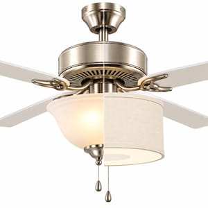 May include: A ceiling fan with a brushed nickel finish and five white blades. The central light fixture is split into two styles: one side features a frosted glass bowl, while the other side has a cylindrical fabric shade. Two pull chains are attached.
