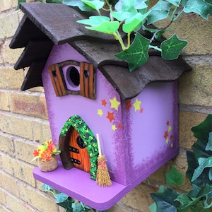 Stunning hand painted wooden bird house in purple.  Features a fairy door, window, stars and a basketfull of flowers.  A great birthday gift