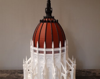 Puede incluir: Un modelo 3D impreso en blanco de un edificio con una cúpula roja y una aguja negra. El modelo está detallado con intrincados detalles arquitectónicos.