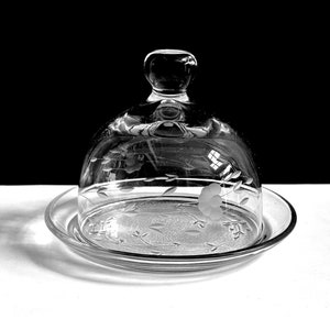 May include: A clear glass cloche with a floral etched design sits on a matching plate. The cloche has a knob on top.