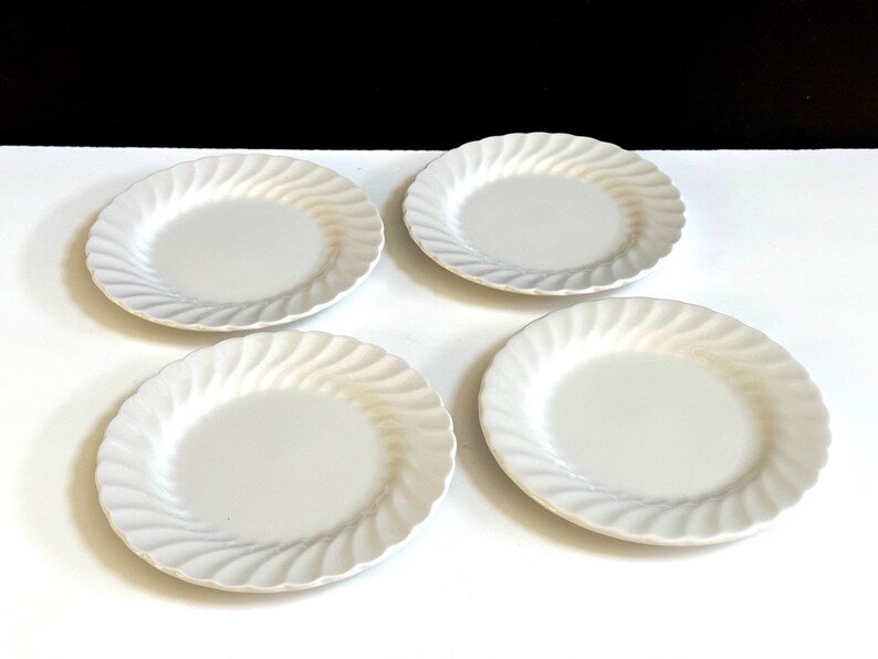 May include: Set of four white ceramic salad plates with a wavy, rippled design.