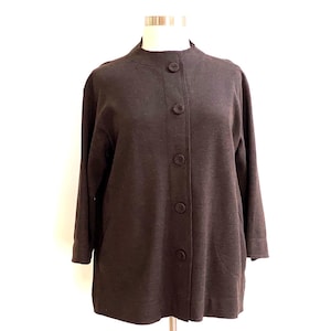 May include: A brown cardigan with a stand-up collar and button closure. The cardigan has long sleeves and a relaxed fit.