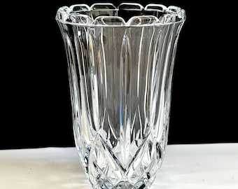 May include: A clear glass vase with a scalloped rim and a flared shape. The vase features vertical and diamond-shaped cut glass patterns, creating a textured and elegant appearance. The vase is suitable for displaying flowers or as a decorative piece.