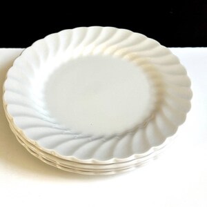 May include: A set of three white ceramic dinner plates with a wavy, scalloped edge.