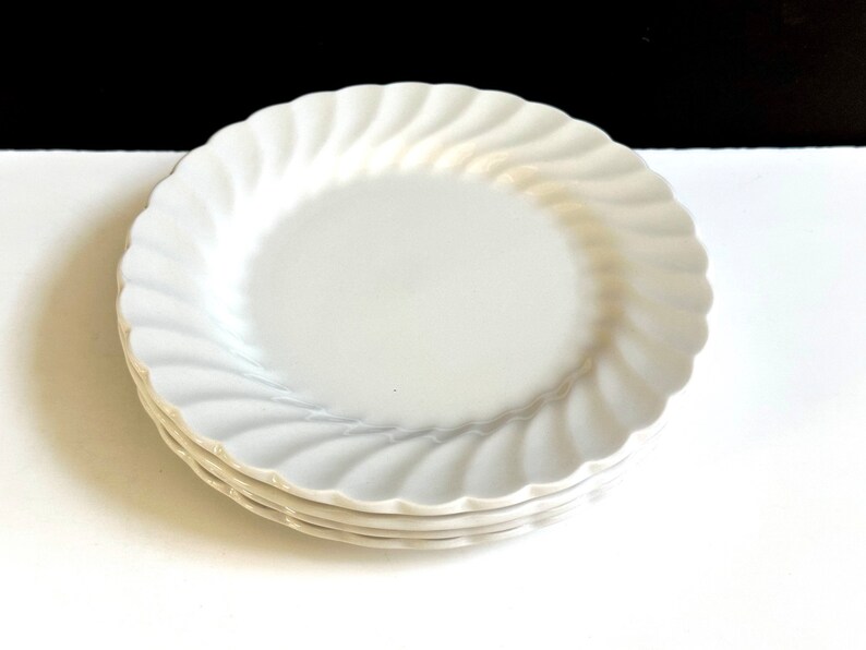 May include: A set of three white ceramic dinner plates with a wavy, scalloped edge.