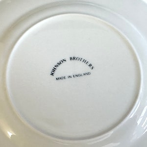 May include: White ceramic plate with a black inscription that reads "Johnson Brothers Made in England".